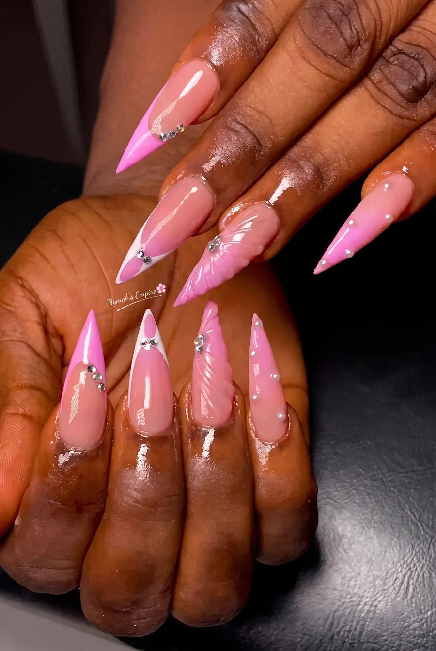 Long pink stiletto nails with crystal accents, carved shell-shaped detail and pearl embellishments